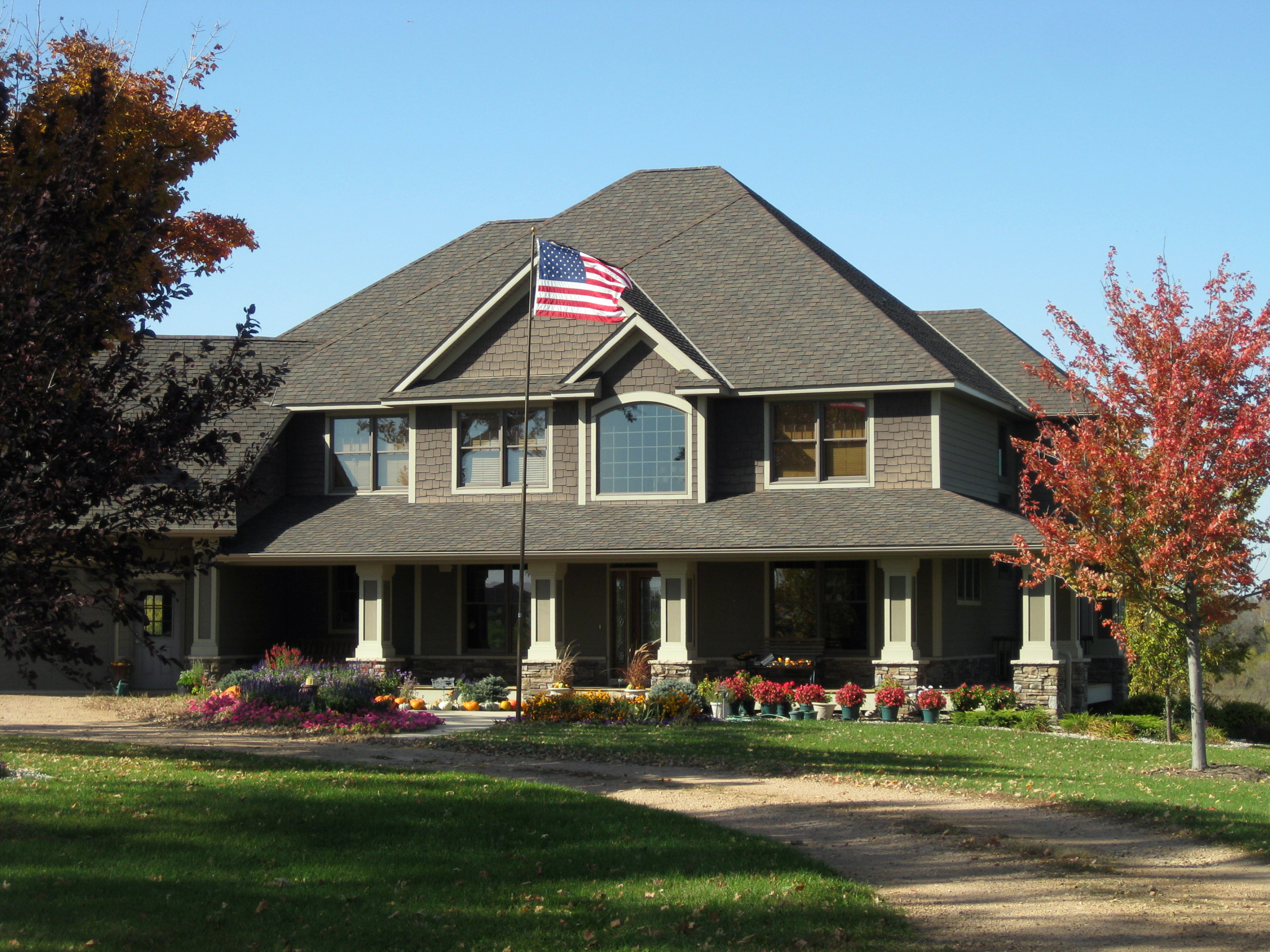 Olive house with front porch and American flag