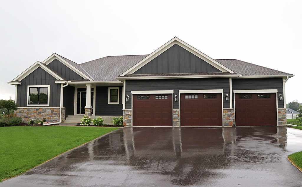 Rambler with three-stall garage, stone wainscoat, board and batten siding and wide accent trim