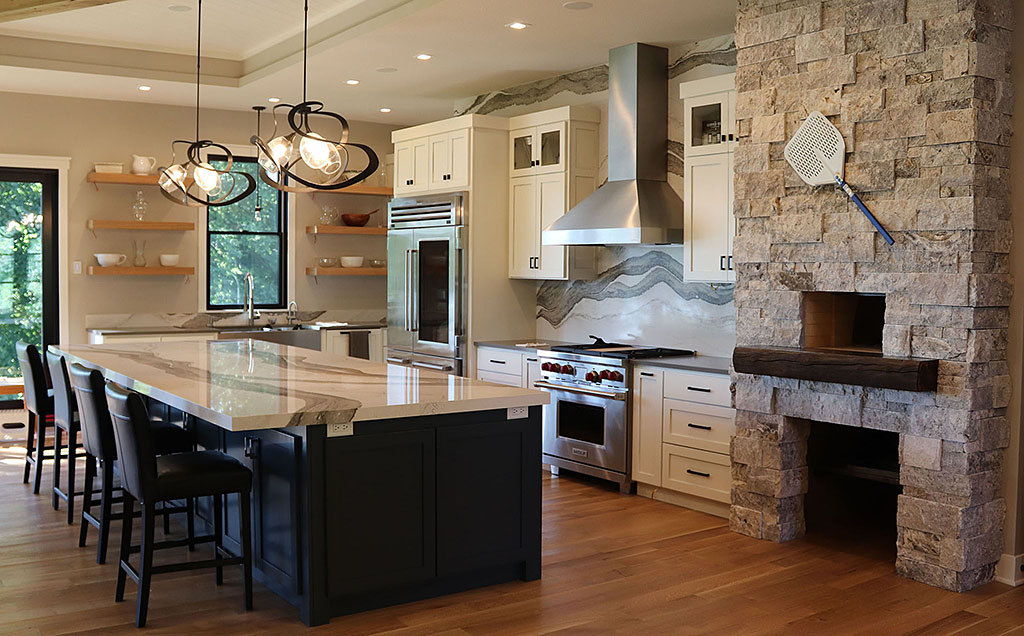 Spacious kitchen with digitally designed Cambria countertop and backsplash, brick oven, white cabinetry and floating shelves