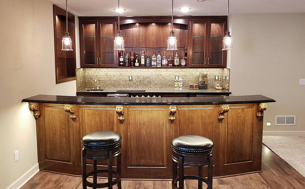 Basement bar area with curved bartop, stone backsplash, custom built-in cabinets with glass doors & shelves