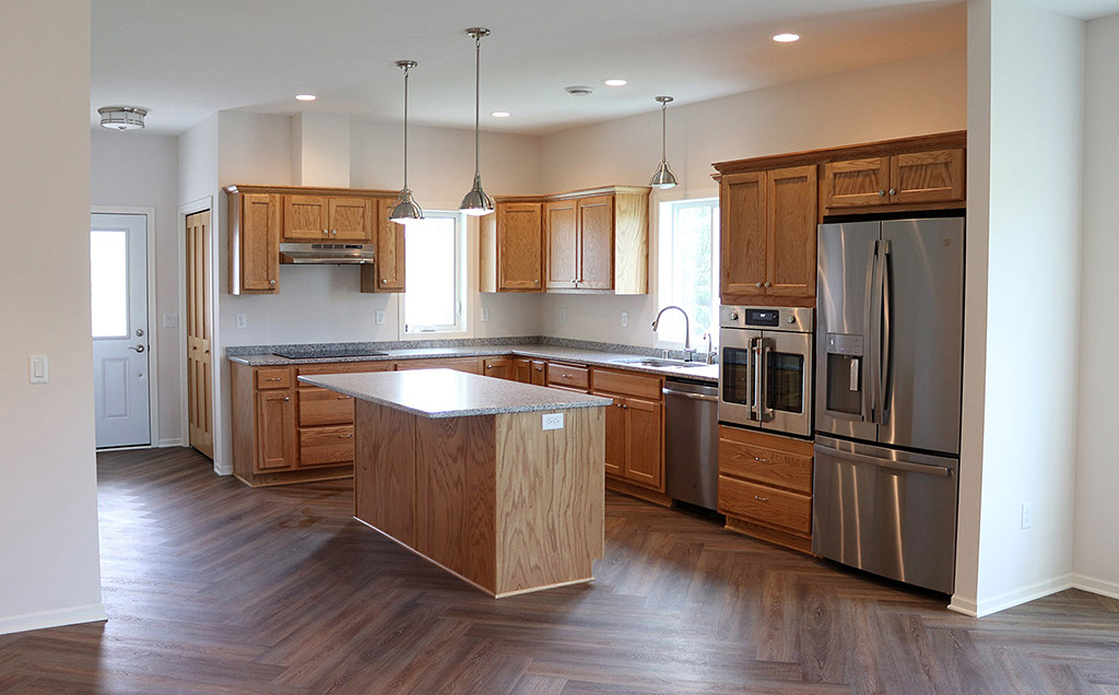 Kitchen with wood cabinets, stainless appliances and herringbone wood floor