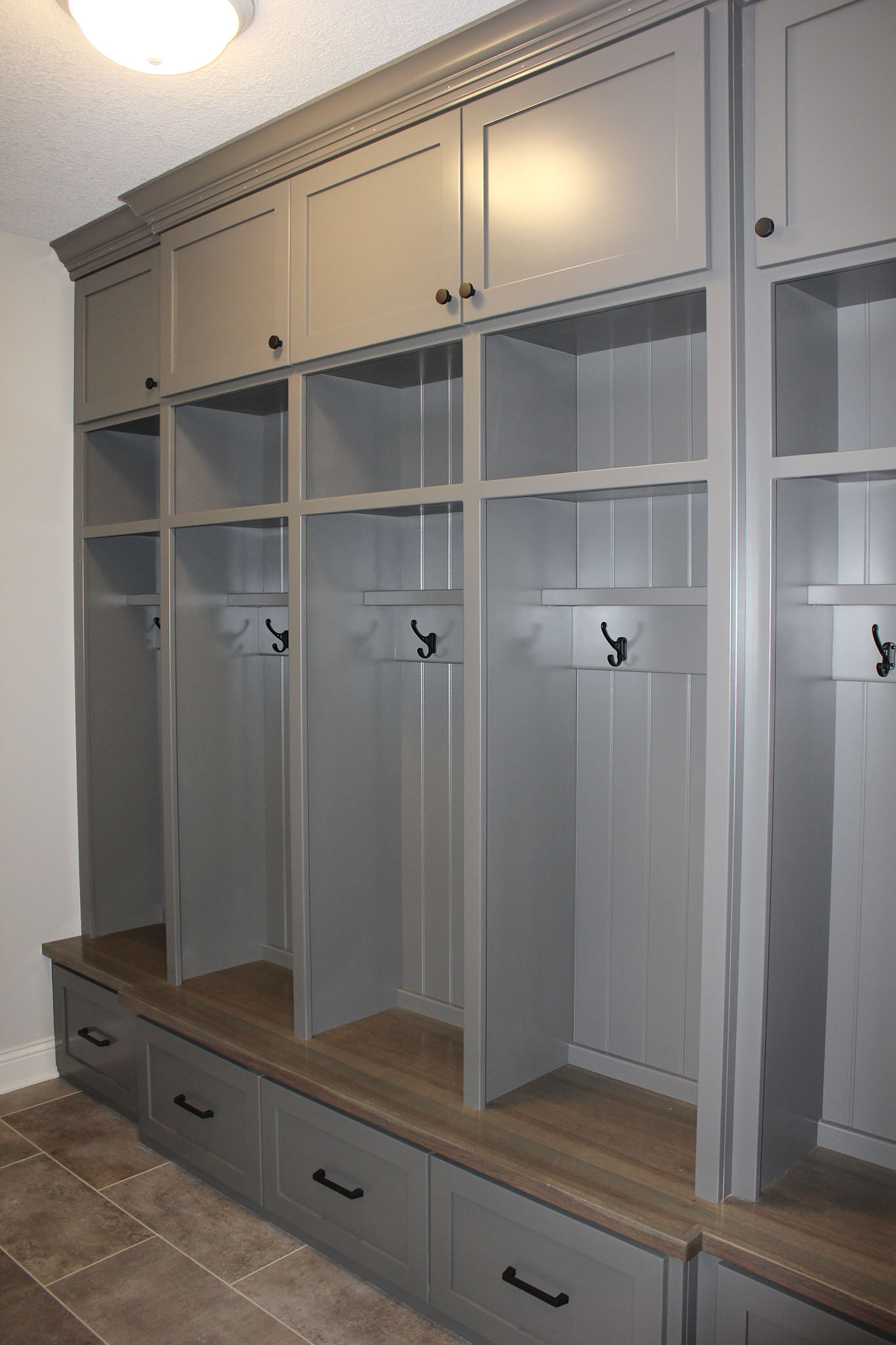Mudroom custom individual locker system with wood seat, coat hooks, drawer storage below, shelf and cabinet storage above